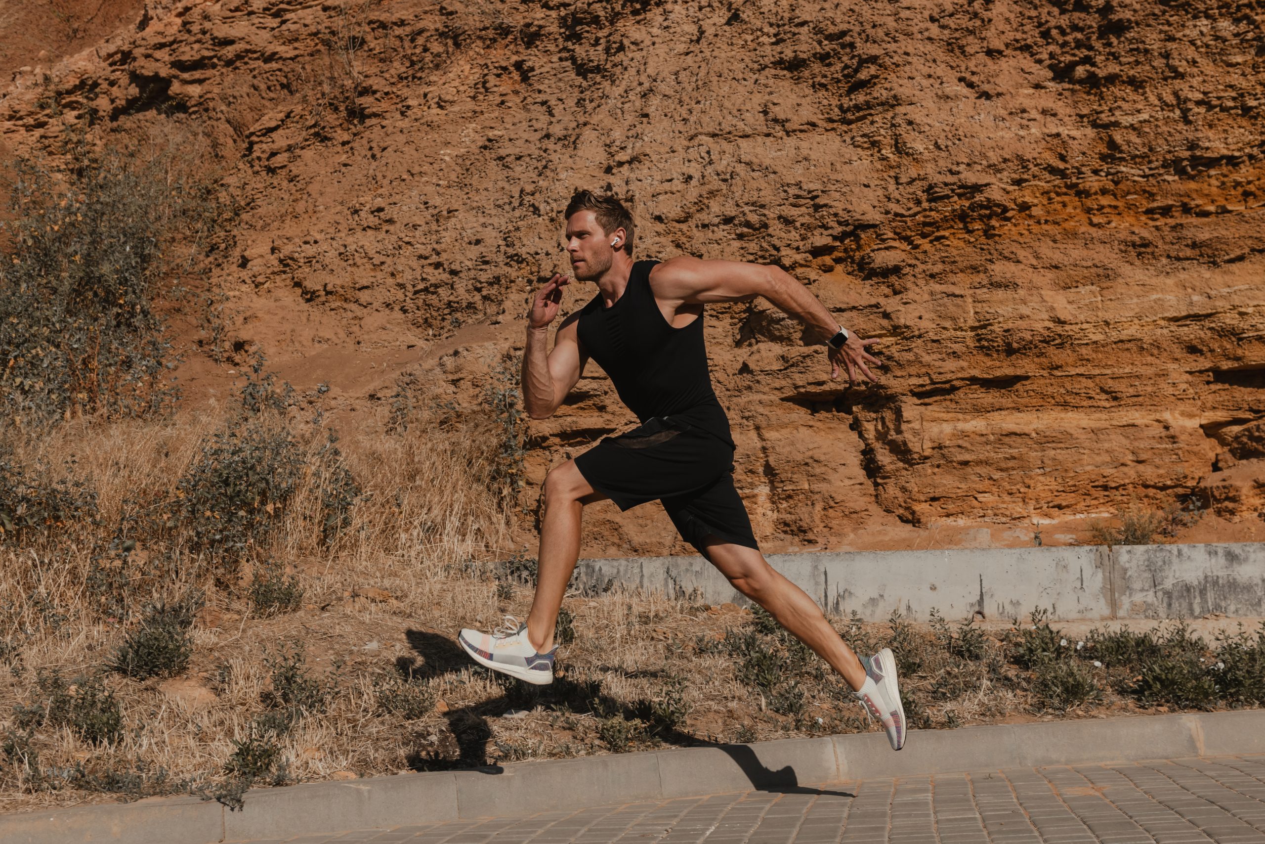 Athletic young man in sports clothing running against rocky mountain outdoors