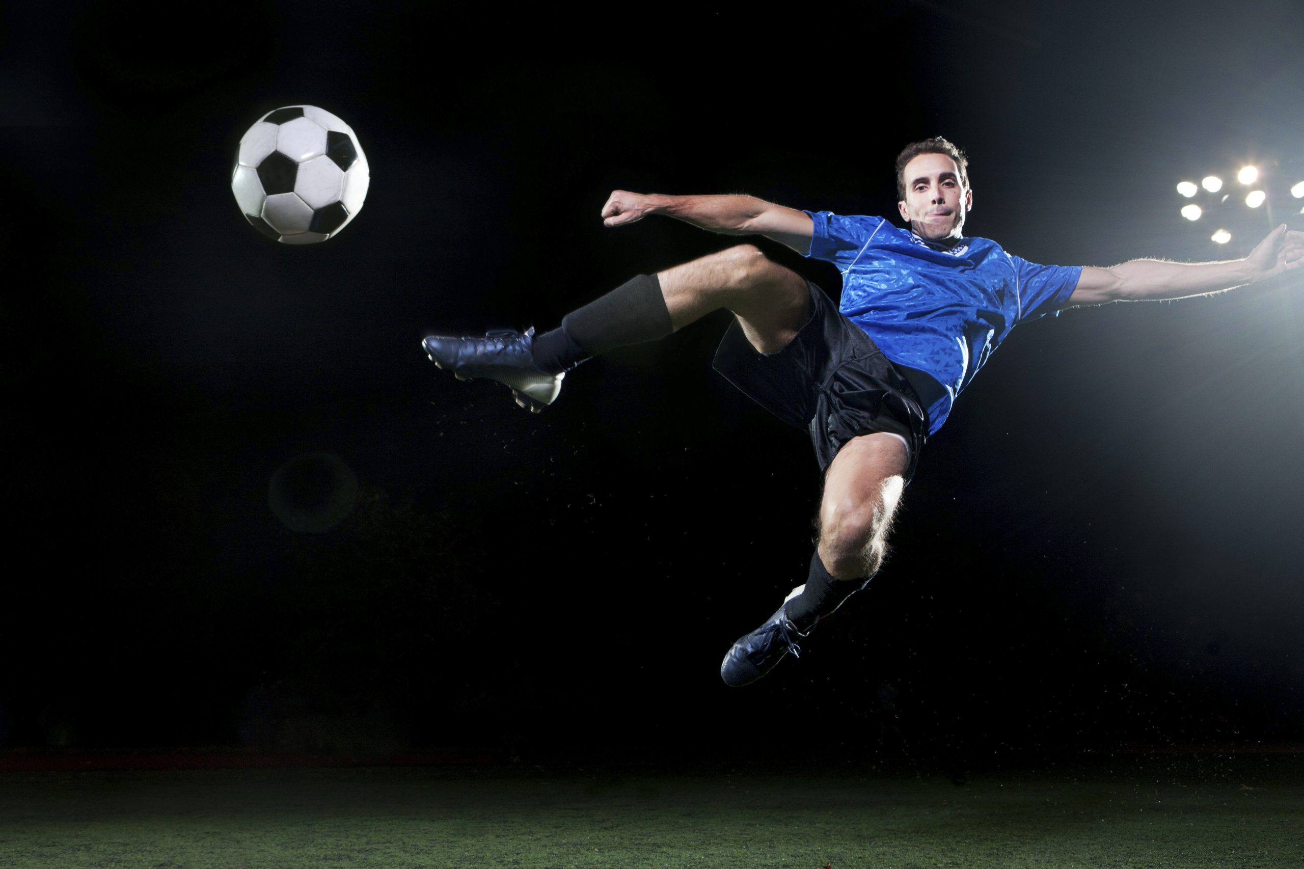 Soccer player performing a midair kick at night